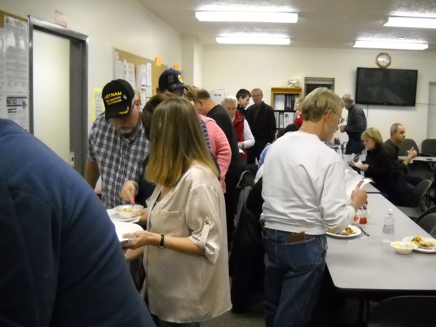 2014 Christmas Potluck, people standing in buffet line serving themselves